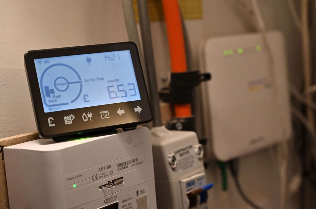 Smart energy monitor showing current cost and monthly usage, mounted on an electrical panel in a utility room.