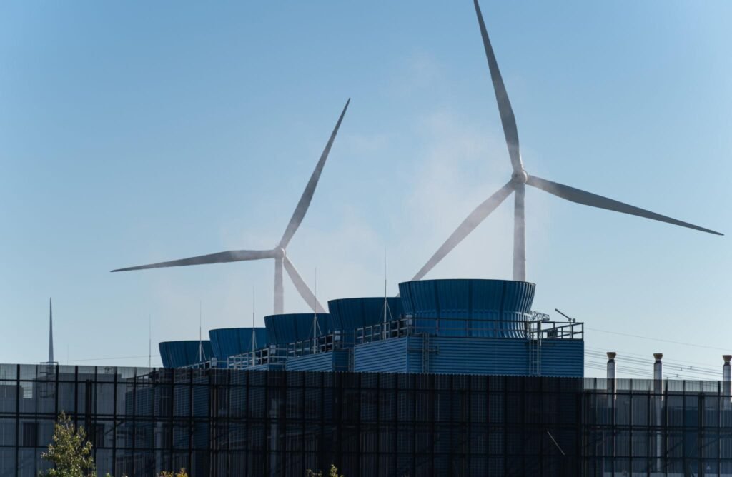 Wind turbines mounted on top of a modern blue-glass building against a clear sky, signaling renewable energy.