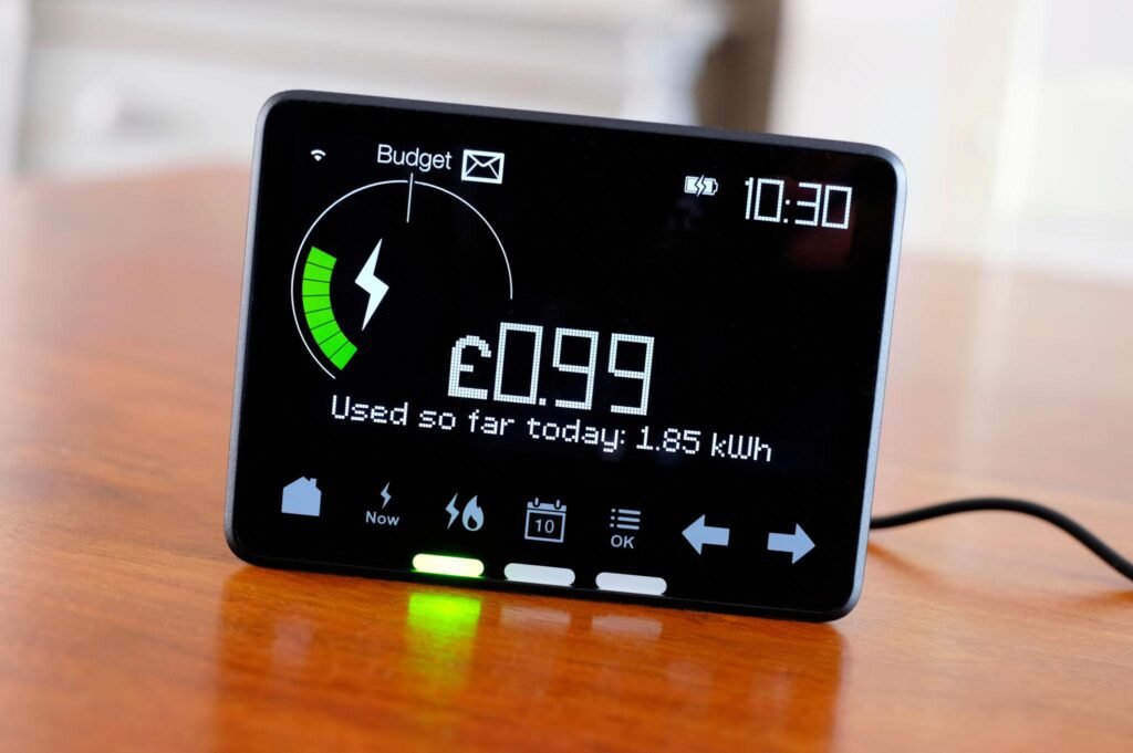 Handheld energy monitor display with a circular gauge showing a green arc, Budget label, time 10:30, and 'Used so far today: 1.85 kWh'